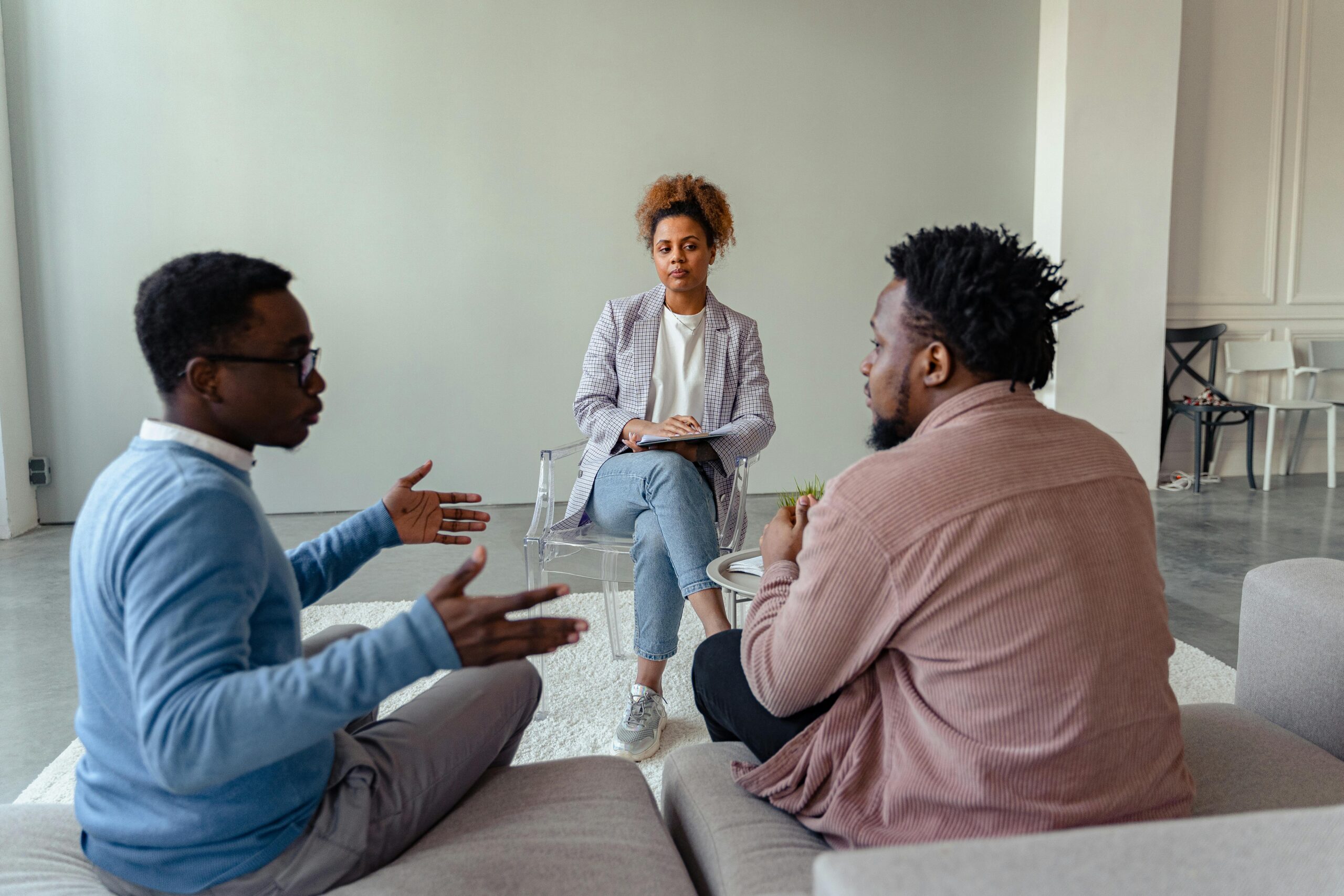 Legal Practice Area A therapist mediates a session with two men on a couch discussing mental health.