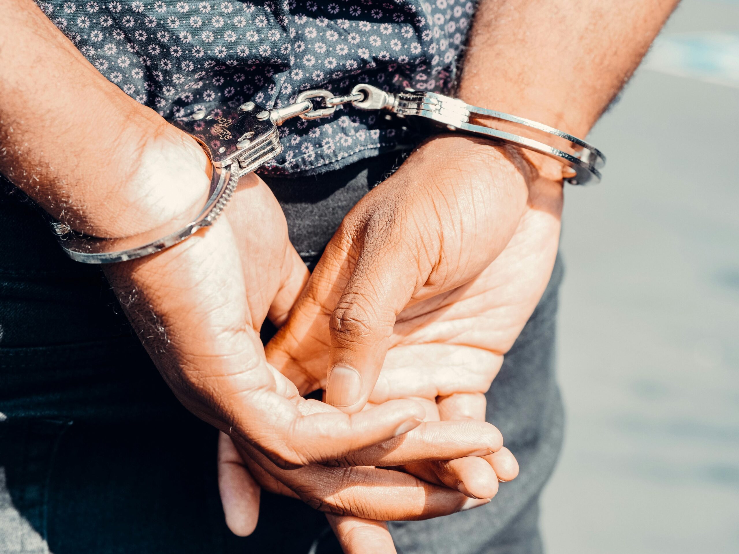 Legal Practice Area Close-up of an adult male's hands in handcuffs, symbolizing law enforcement and justice.