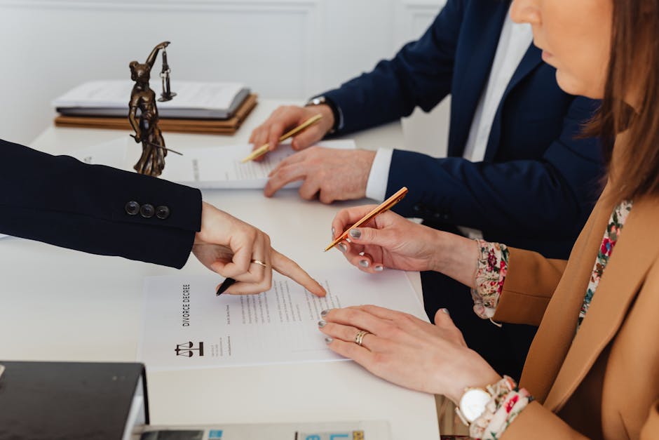 Legal Practice Area Hands signing a divorce decree, with a justice statue nearby, symbolizing legal proceedings.