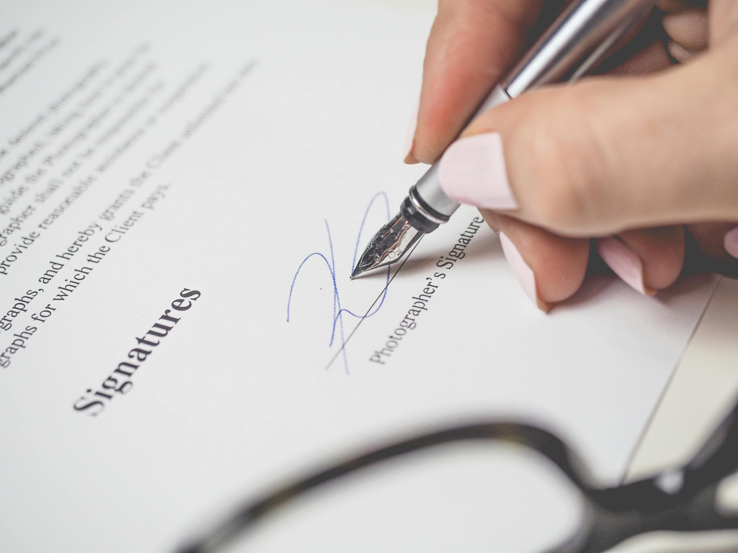 Legal Practice Area Close-up of a hand signing a contract, showcasing a pen and elegant handwriting.