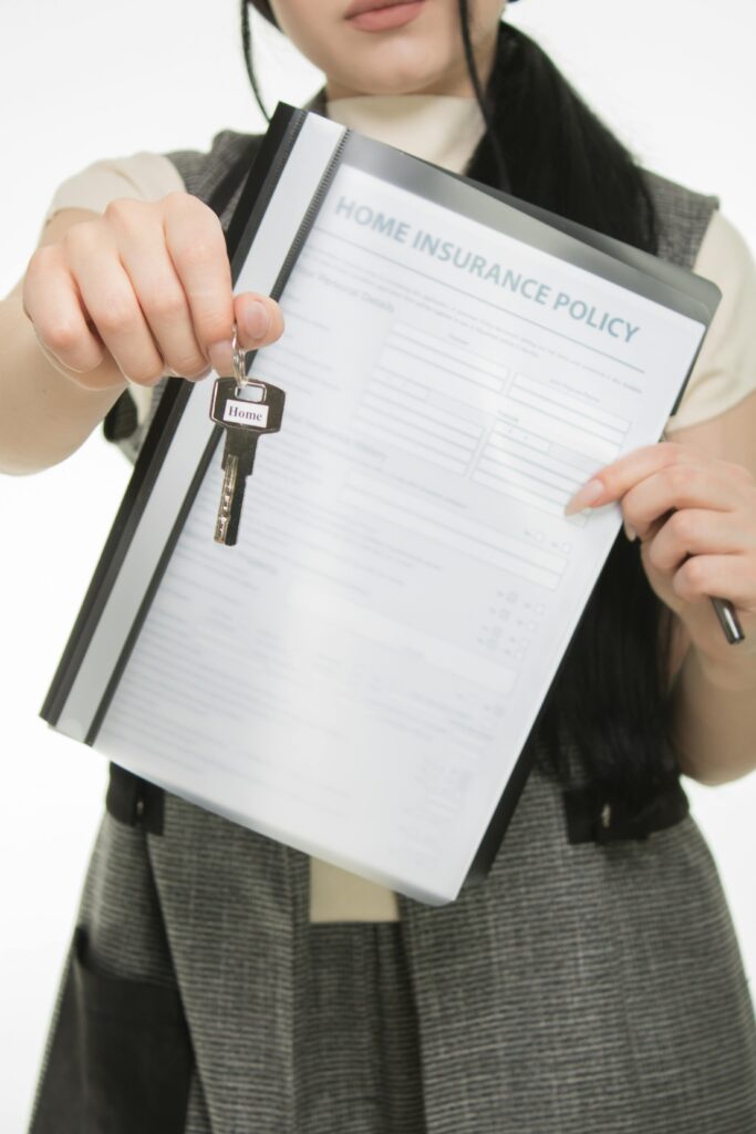 Rera Advocate Close-up of person holding home insurance document and house key, symbolizing real estate and security.