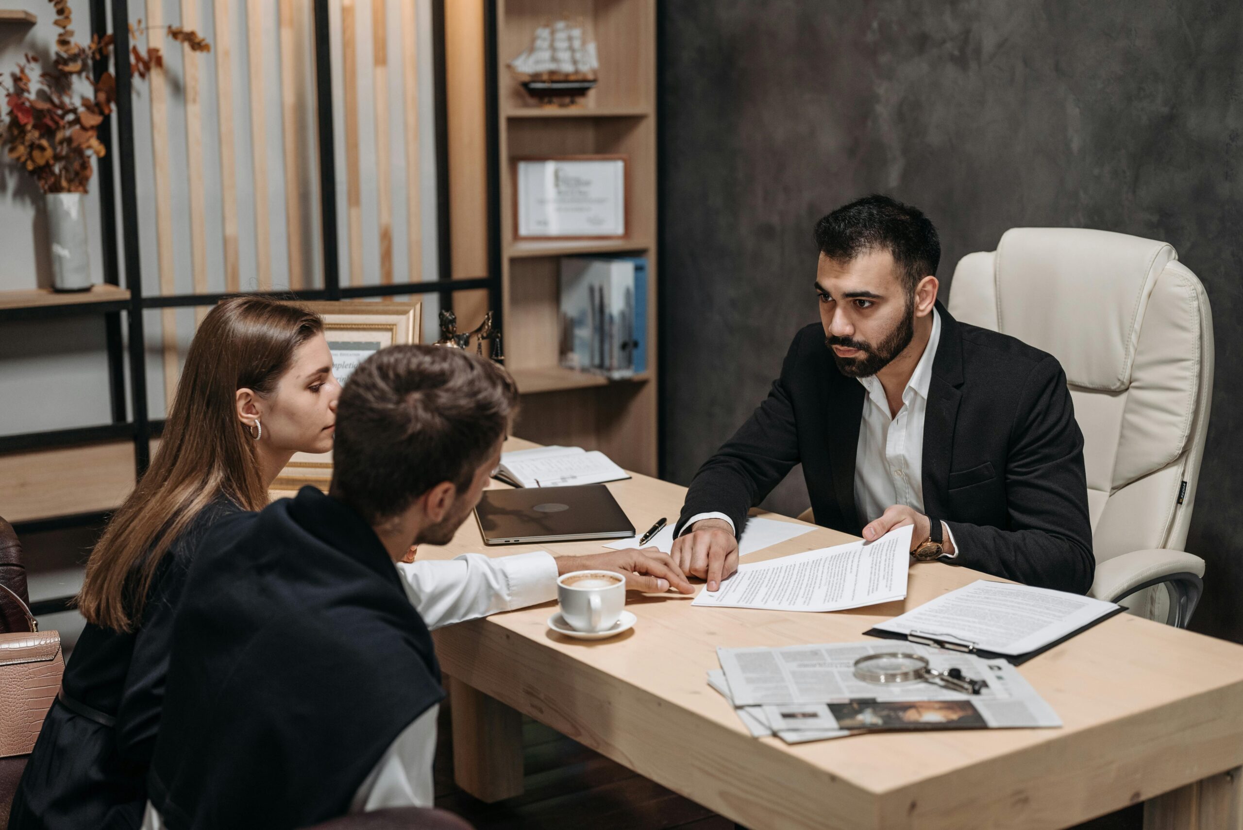 Rera Advocate Lawyer discussing legal documents with clients at office desk.